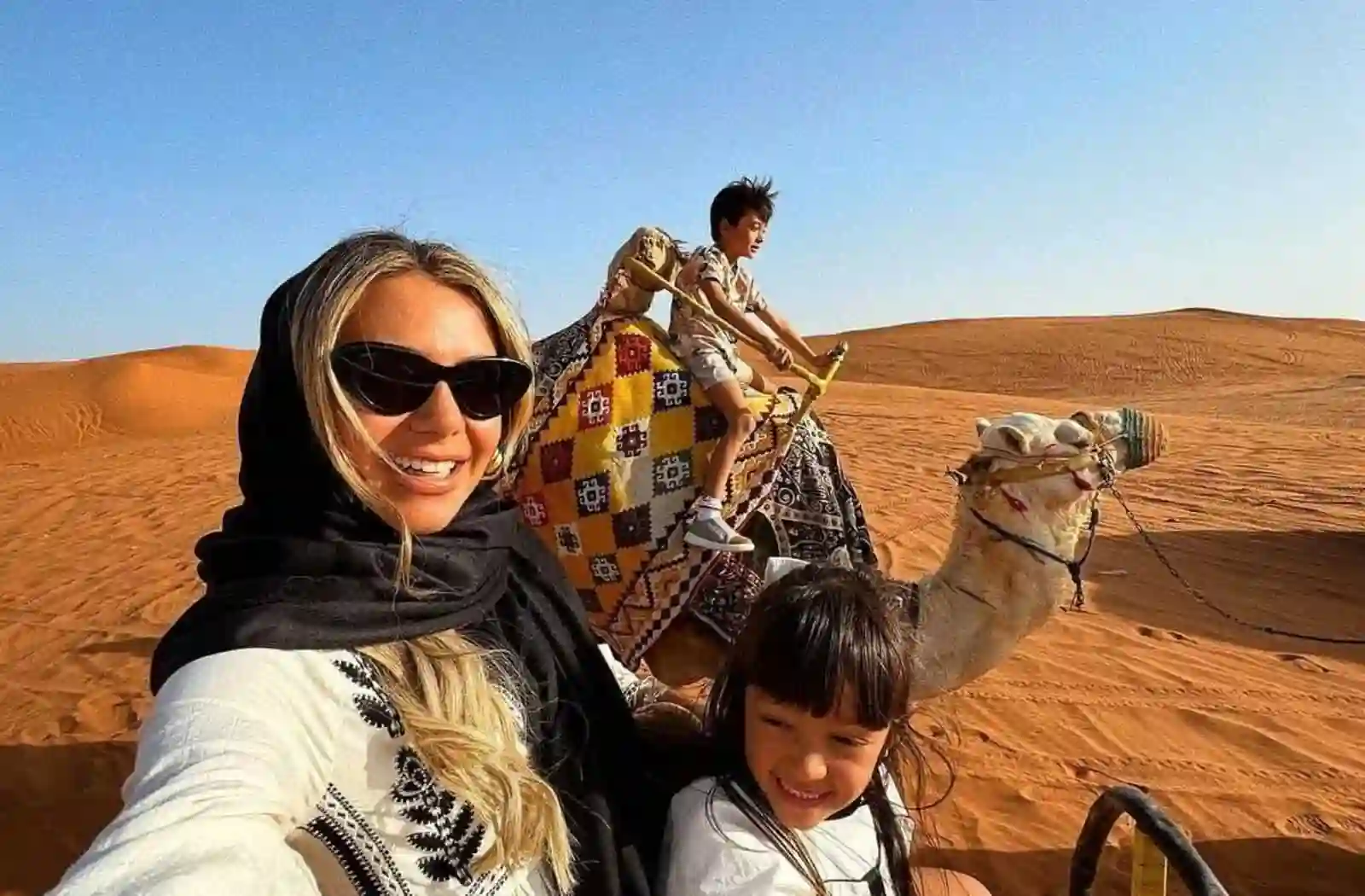 Guests taking a selfie while enjoying a camel ride during a desert safari in Dubai