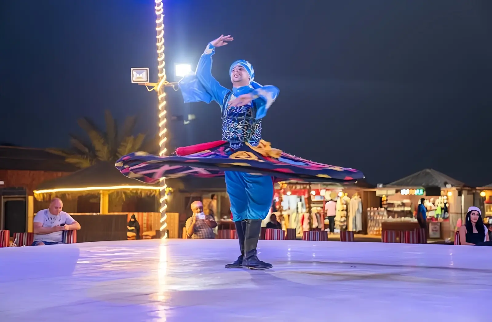 Guests enjoying a live traditional tanoura dance show during an evening desert safari in Dubai.