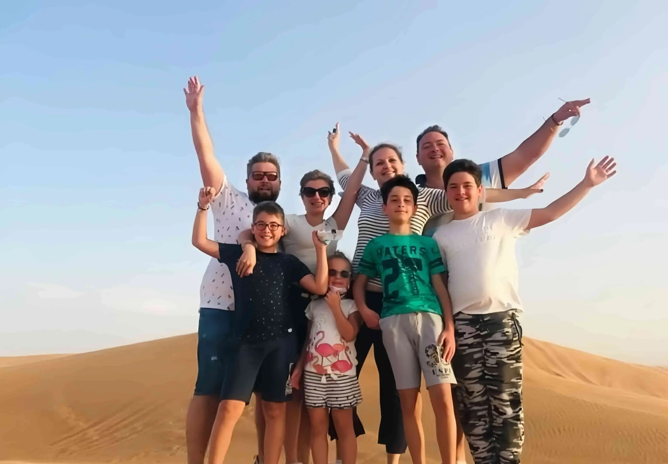 Family posing together on the sand dunes during a morning desert safari in Dubai