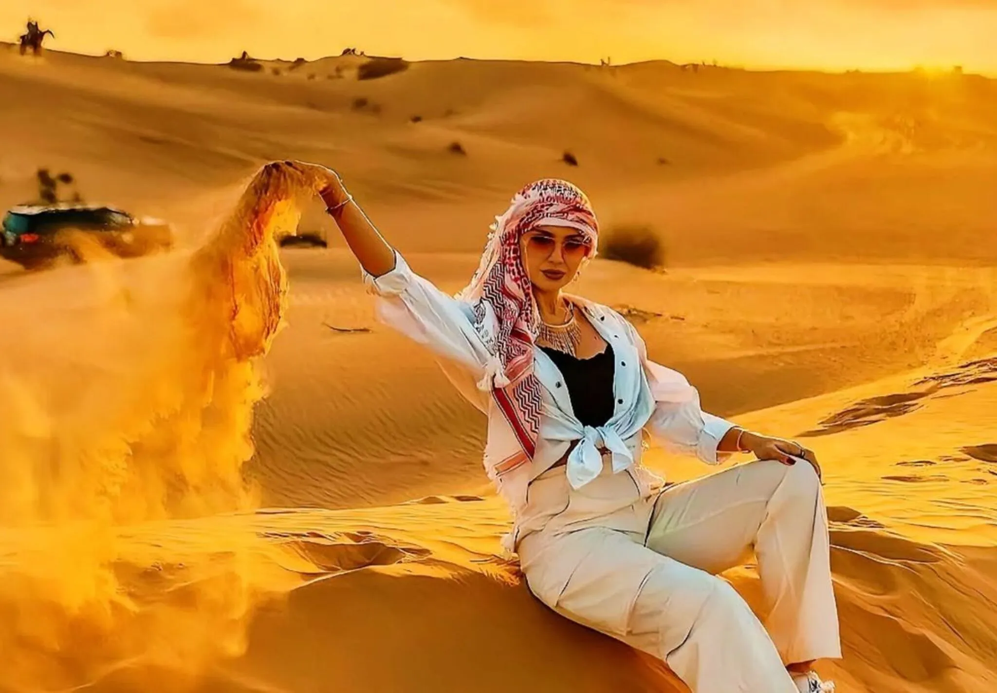 Female guest letting sand fall from her hand during a morning desert safari in Dubai