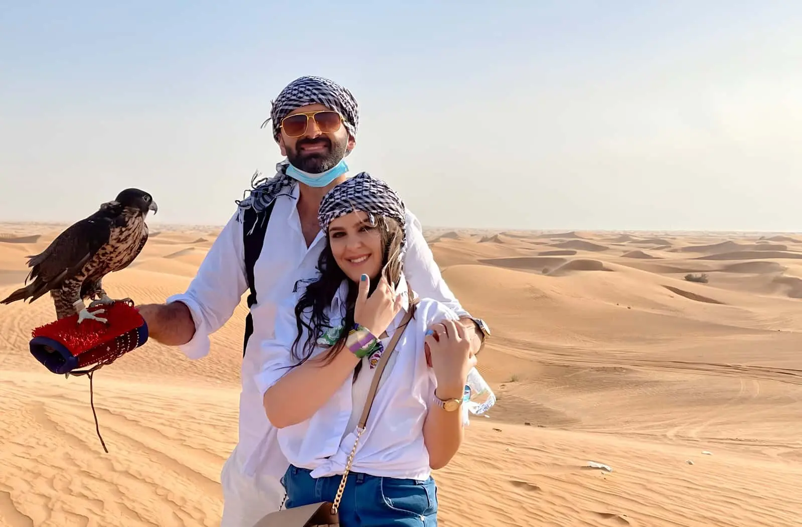 Couple posing with a trained falcon during a premium desert safari in Dubai.