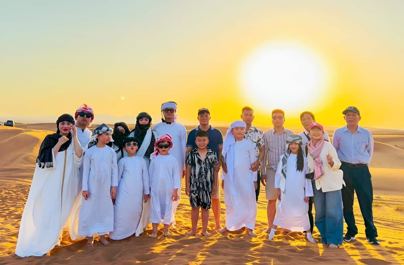 Family posing for a sunset picture on the golden sand dunes during a premium desert safari in Dubai.