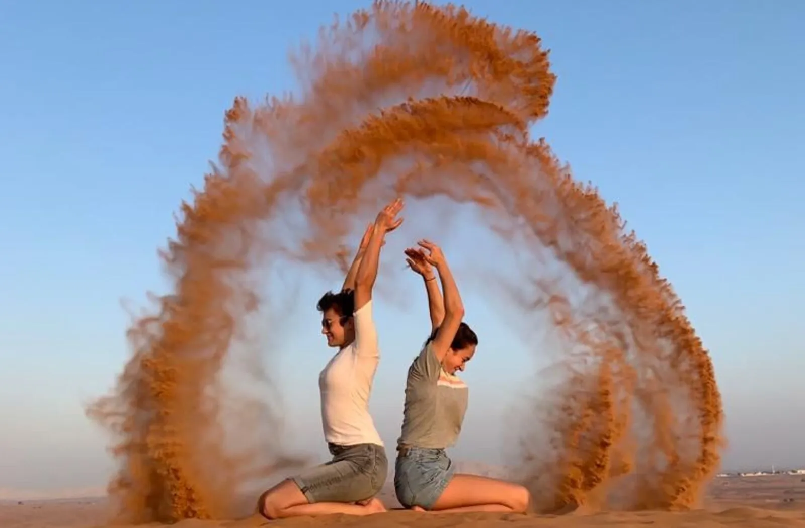 Couple tossing sand for a memorable photo during a desert safari in dubai